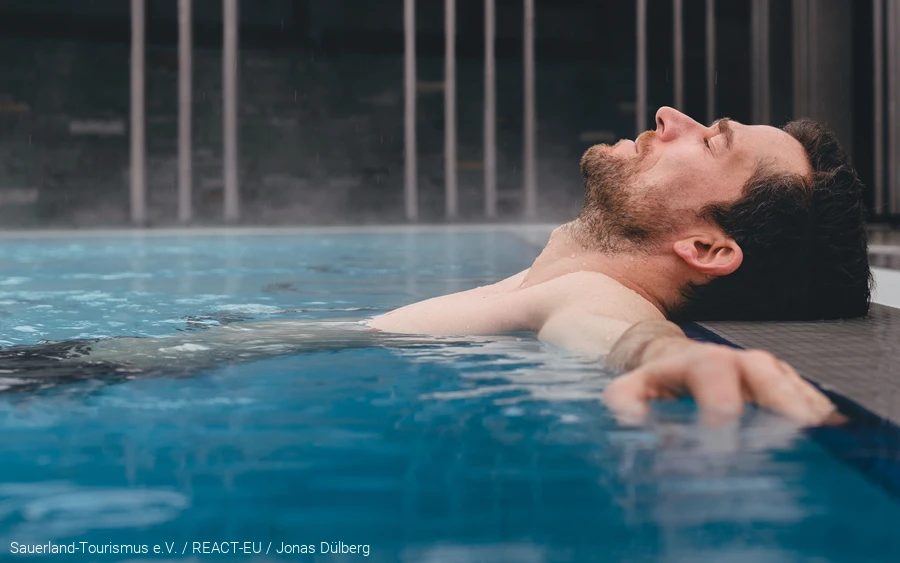 Ein Mann liegt im Thermalbecken von der Börde Therme in Bad Sassendorf. Er entspannt.