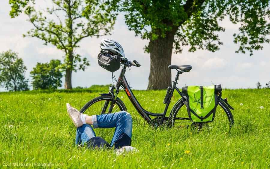 Lippetal. Eine Frau liegt auf der Wiese. Dahinter steht ein Fahrrad. AG LSG Route: Fotografie Golz