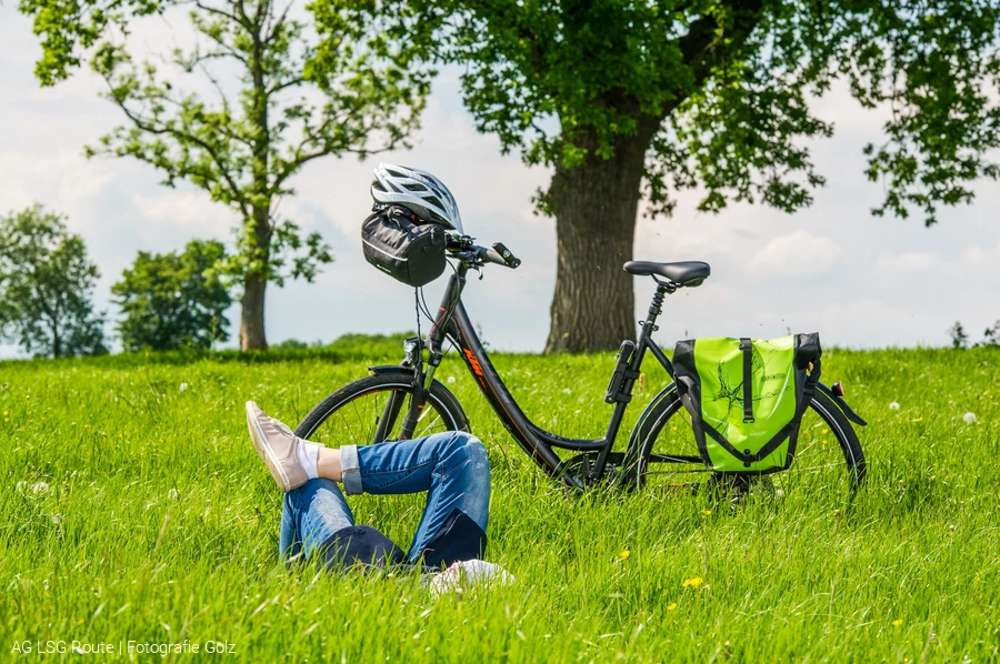 Lippetal. Eine Frau liegt auf der Wiese. Dahinter steht ein Fahrrad. AG LSG Route: Fotografie Golz